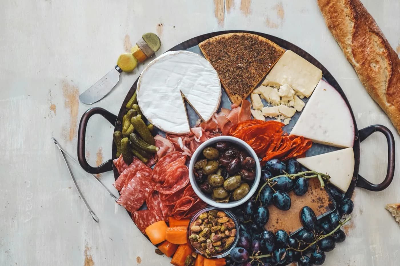 A finished charcuterie board with cheeses, cured meats, olives and grapes, from a charcuterie kit