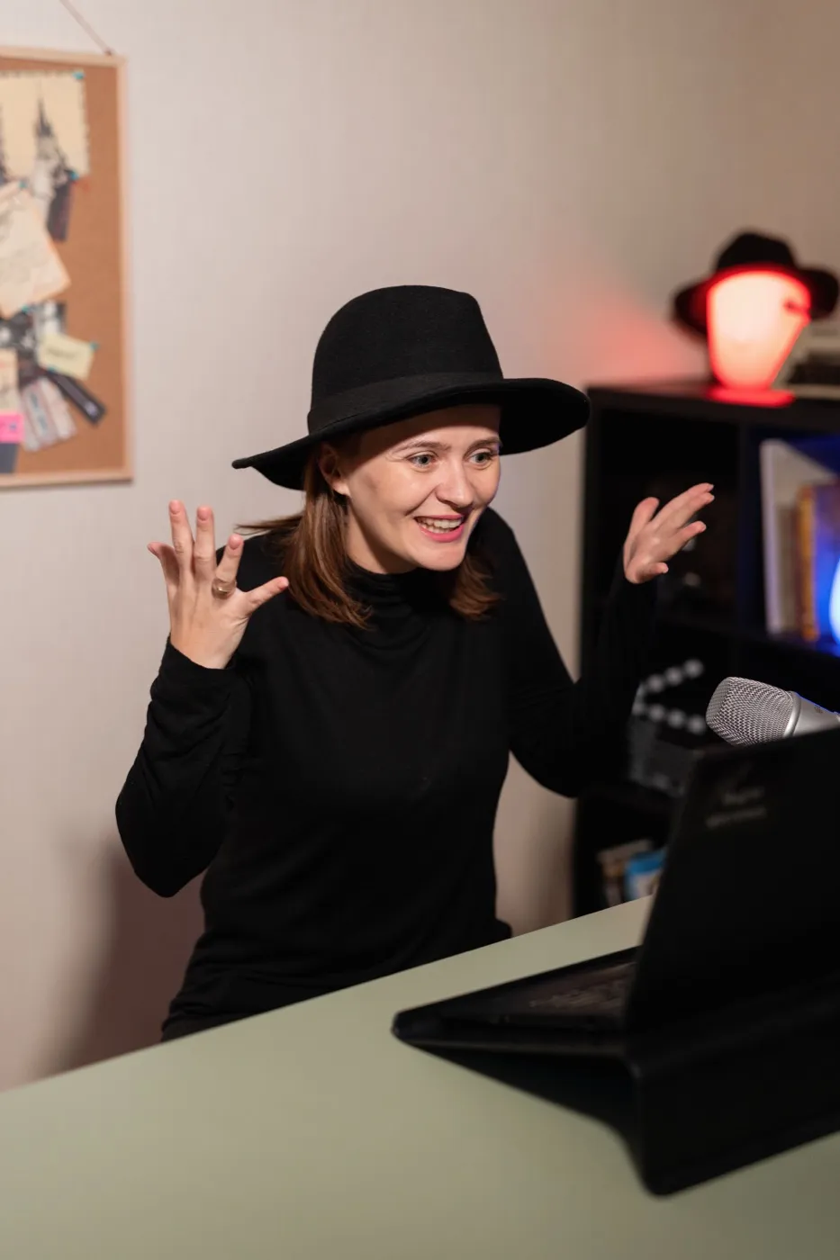 The host, in a black hat, talks to players on a laptop video call