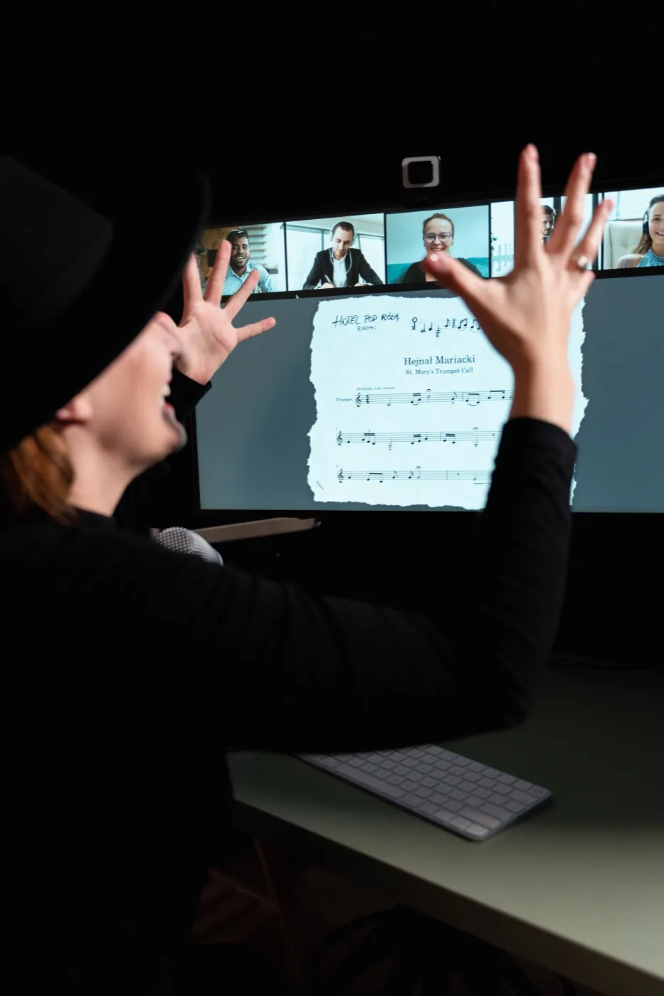 The host shares a clue on a big screen while players watch from their video tiles