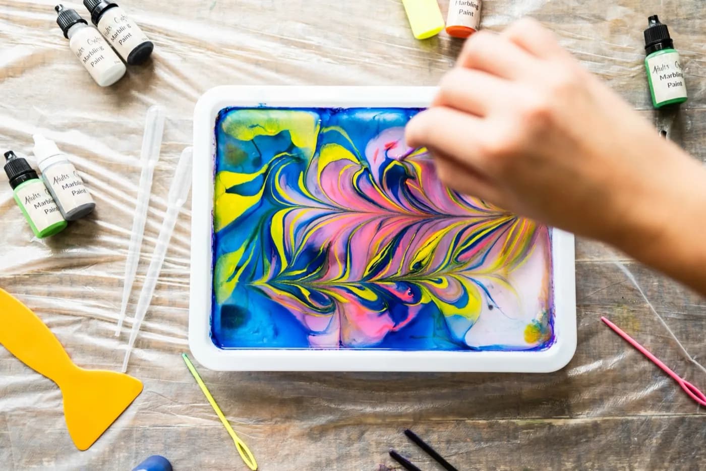 Hands swirling marbling paint on water